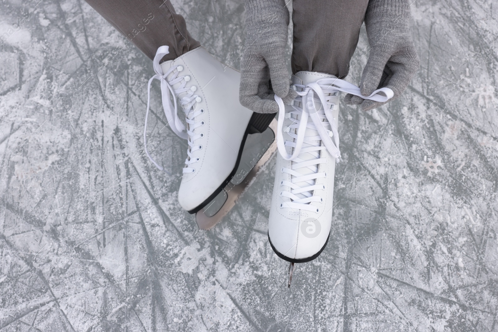 Photo of Woman lacing figure skates on ice, top view