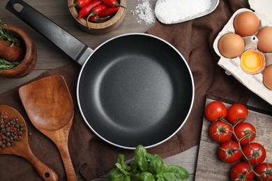 Photo of Flat lay composition with cooking utensils, frying pan and fresh ingredients on wooden table