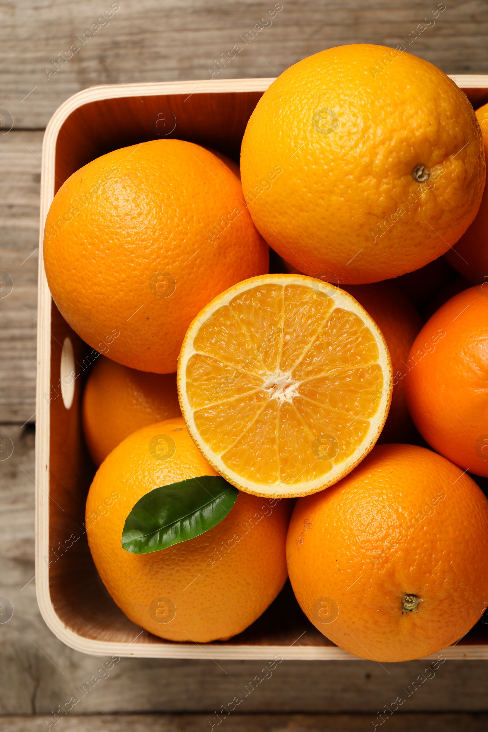 Photo of Many whole and cut ripe oranges on wooden table, top view