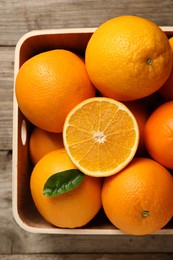 Photo of Many whole and cut ripe oranges on wooden table, top view