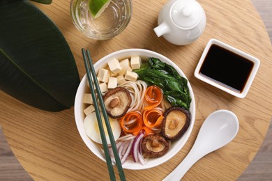 Photo of Delicious vegetarian ramen served on wooden table, flat lay. Noodle soup