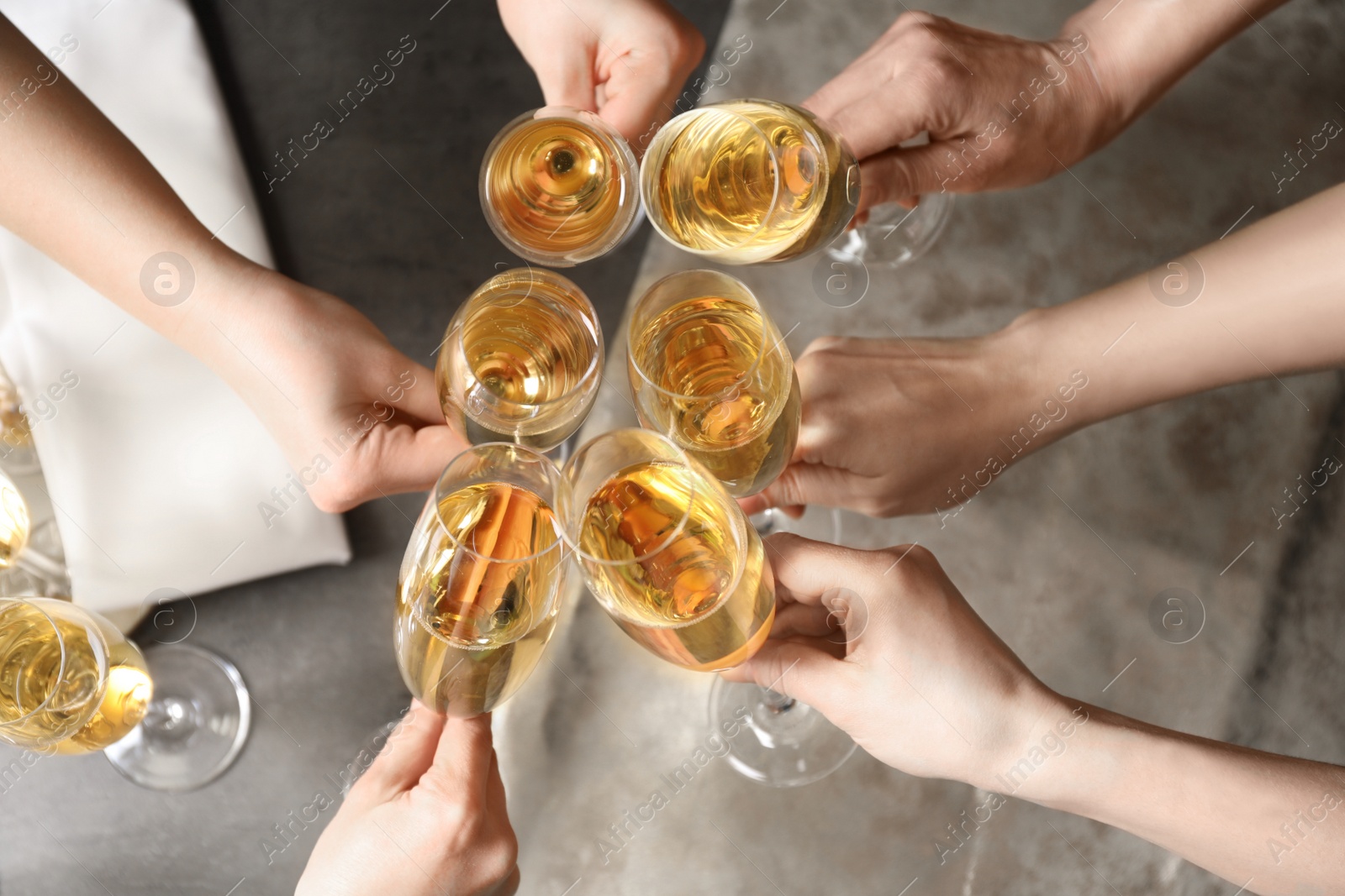 Photo of People clinking glasses with champagne over table, top view