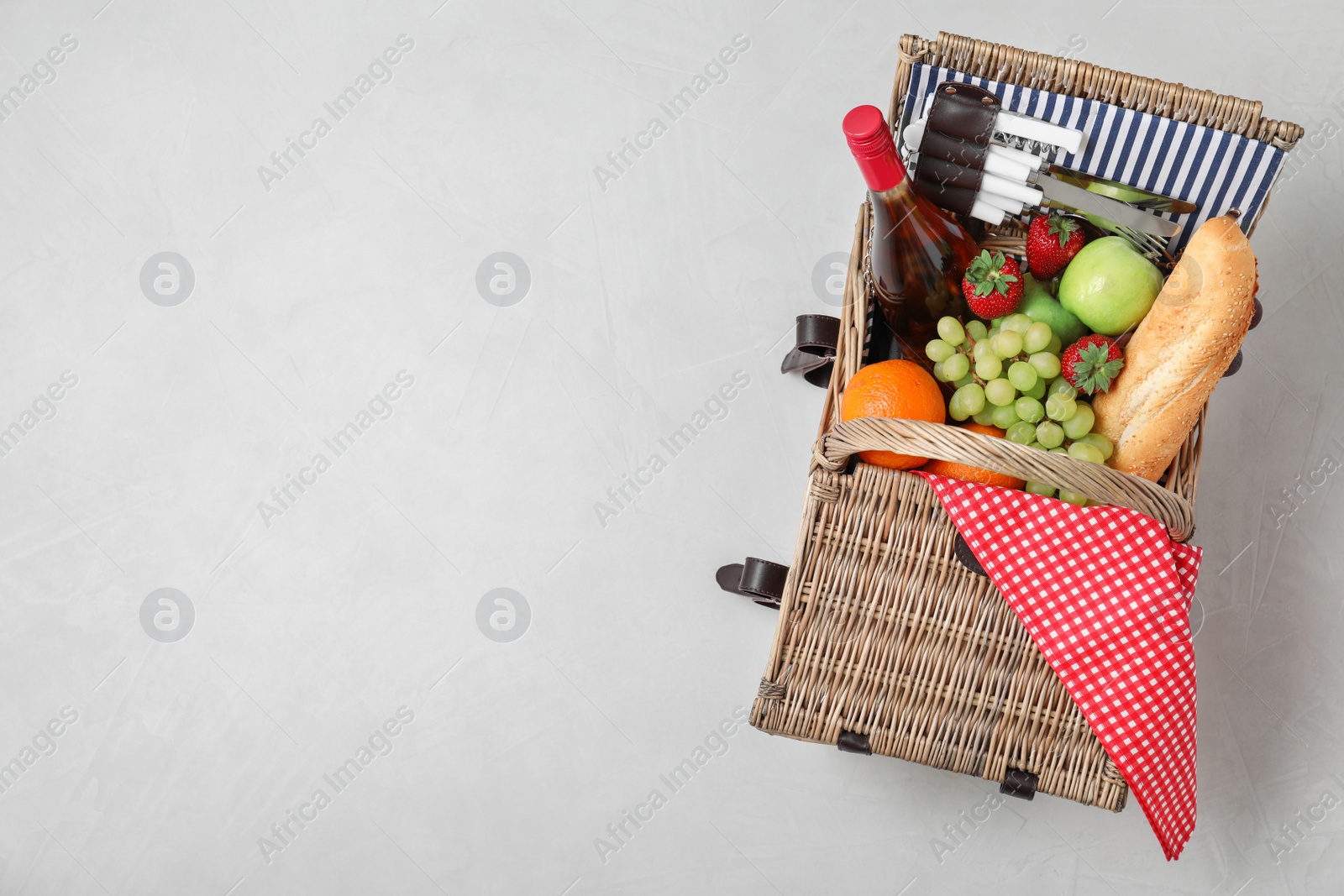 Photo of Wicker picnic basket with wine and different products on white background, top view