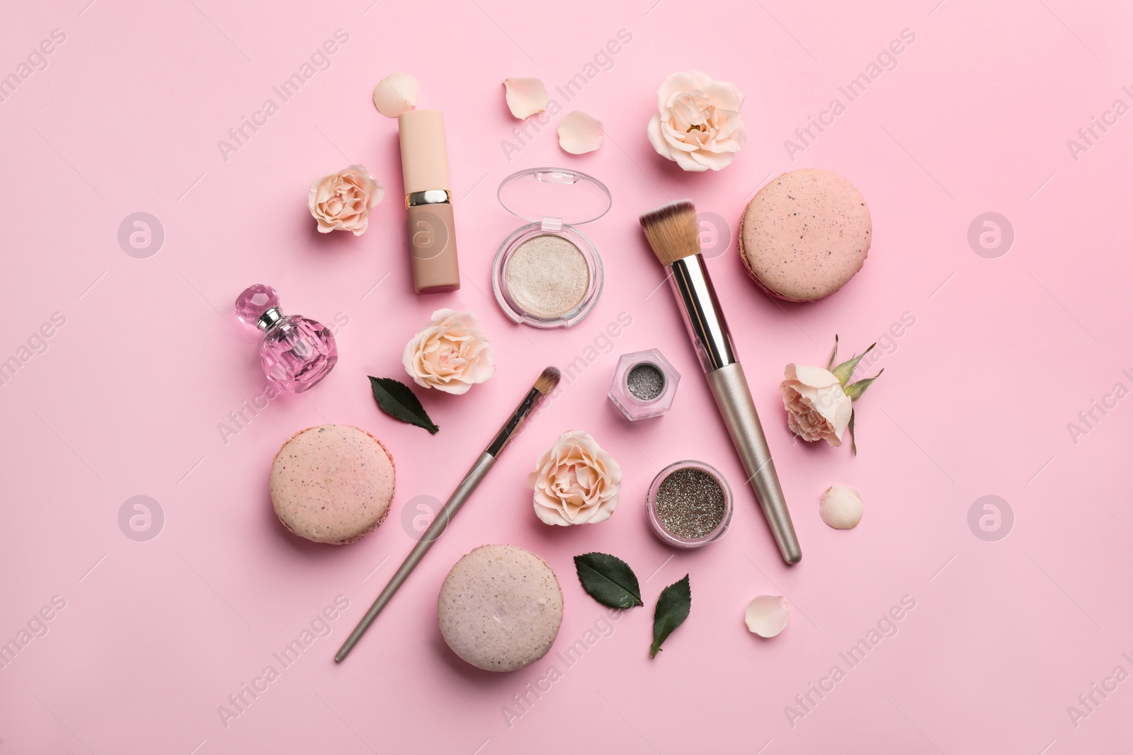 Photo of Flat lay composition with makeup products, roses and macarons on pink background