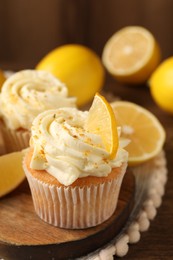 Photo of Tasty cupcakes with cream, zest and lemons on wooden table, closeup