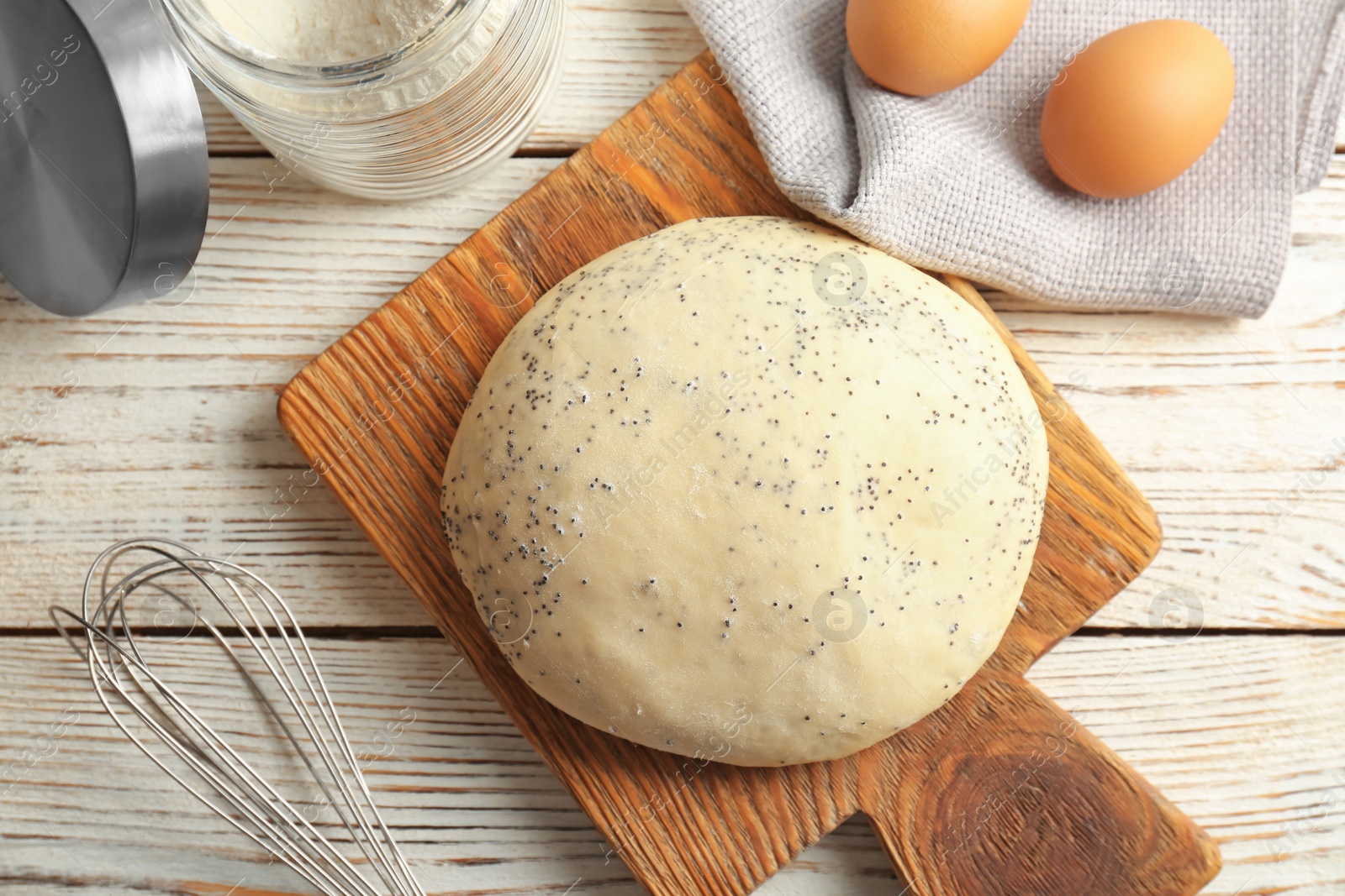 Photo of Raw dough with poppy seeds on wooden board, top view