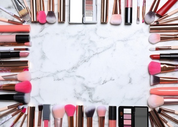 Photo of Frame of different makeup products on white marble table, flat lay. Space for text