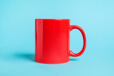 Photo of One red ceramic mug on light blue background