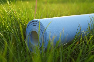 Photo of Blue karemat or fitness mat in fresh green grass outdoors, closeup