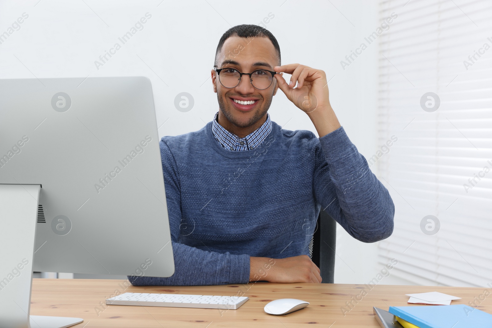 Photo of Happy young intern working at table in modern office