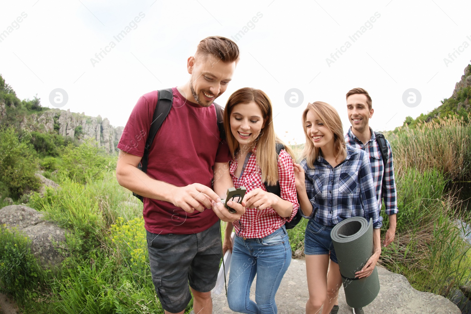 Photo of Group of young people with compass in wilderness. Camping season