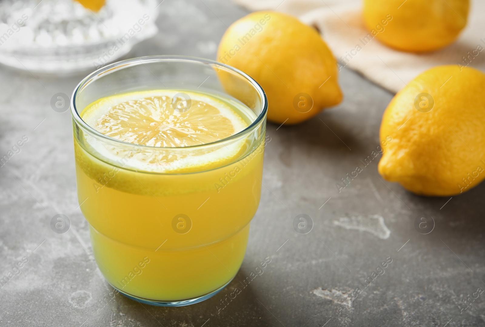 Photo of Glass with fresh lemon juice and fruits on table