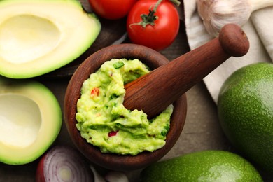 Photo of Mortar with delicious guacamole and ingredients on table, flat lay