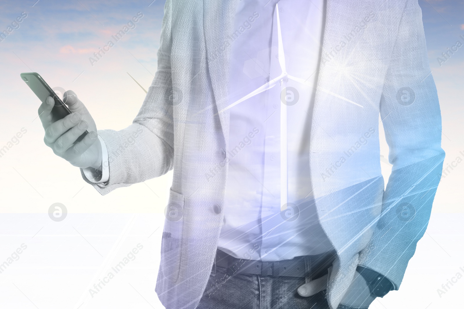 Image of Multiple exposure of businessman with smartphone, wind turbines and solar panels installed outdoors. Alternative energy source