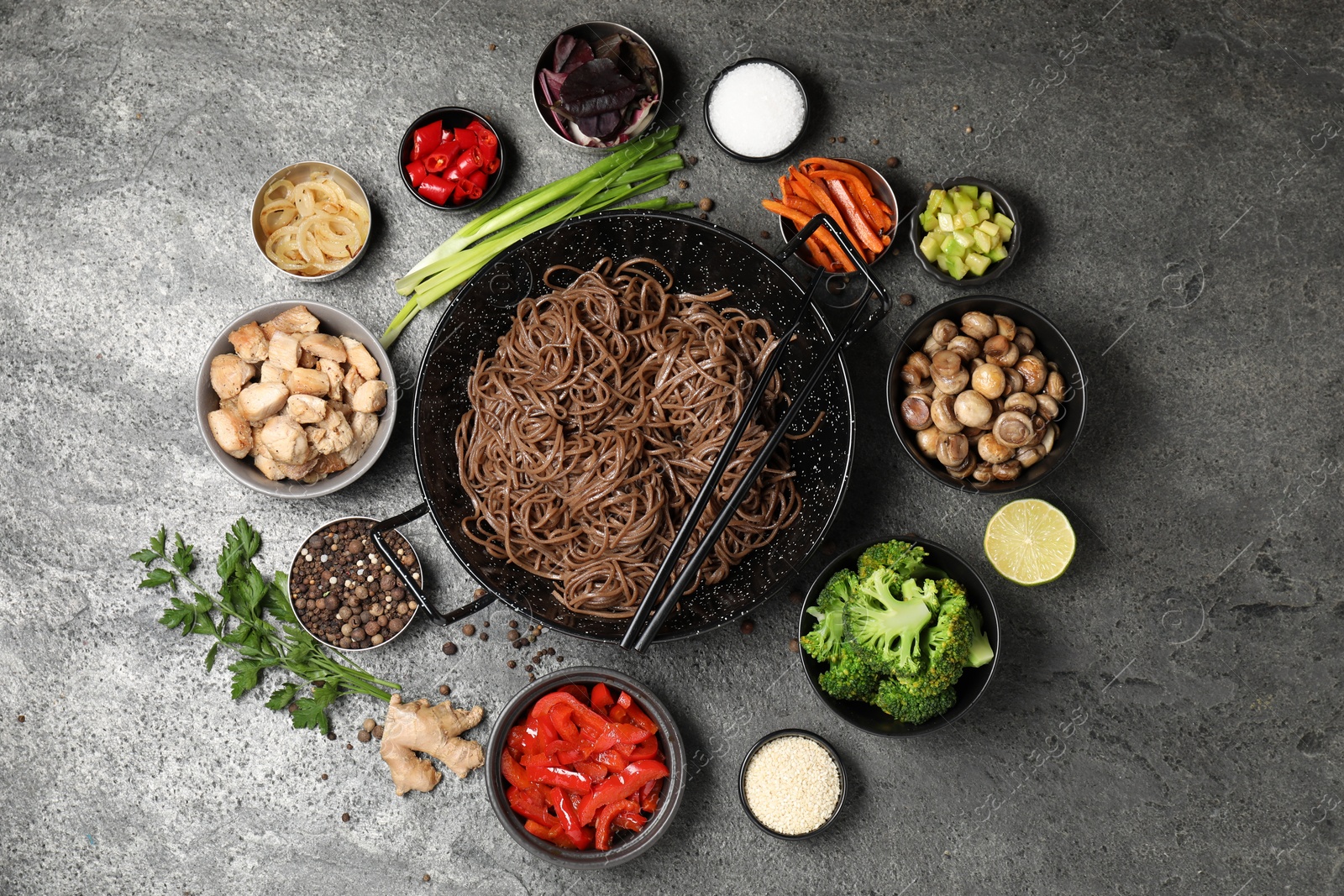 Photo of Wok with noodles, chicken and other products on grey table, flat lay