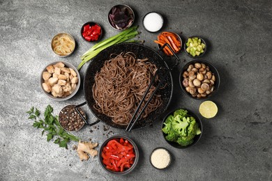 Photo of Wok with noodles, chicken and other products on grey table, flat lay