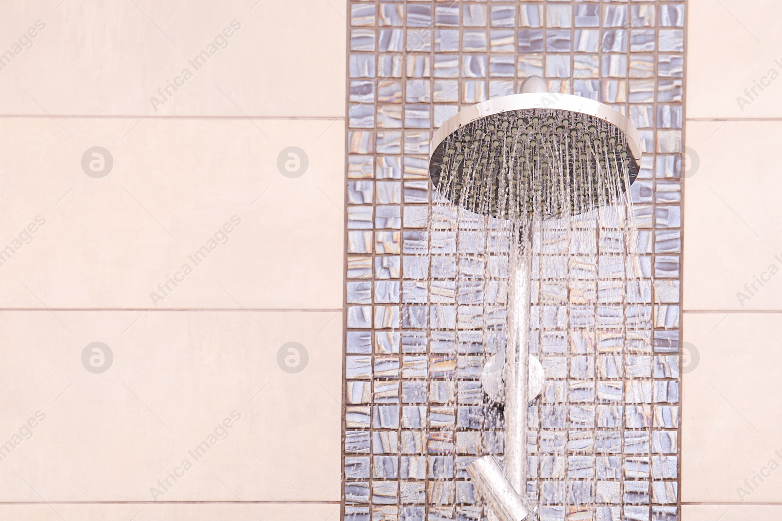 Photo of Shower head with running water in bathroom. Space for text