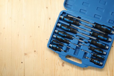 Photo of Set of screwdrivers in open toolbox on light wooden table, top view. Space for text