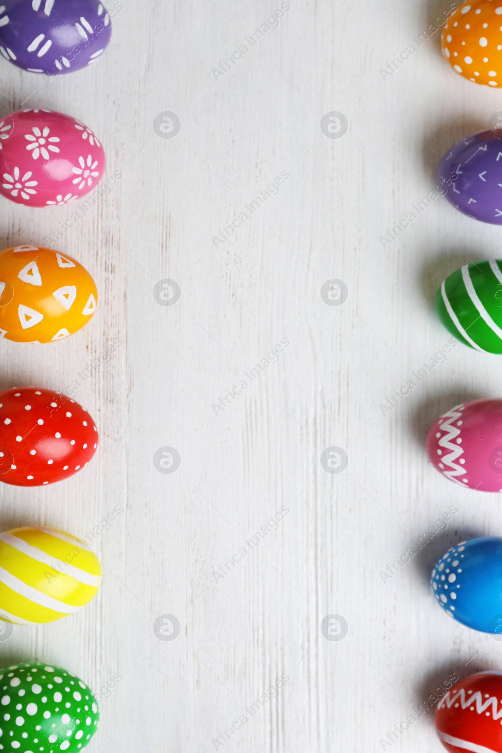 Photo of Decorated Easter eggs and space for text on wooden background, top view