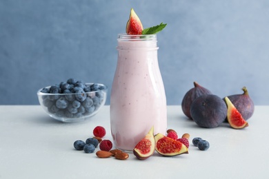 Delicious fig smoothie in glass bottle on white table