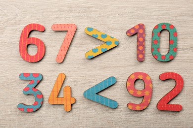 Photo of Colorful numbers and mathematical symbols on light wooden table, flat lay