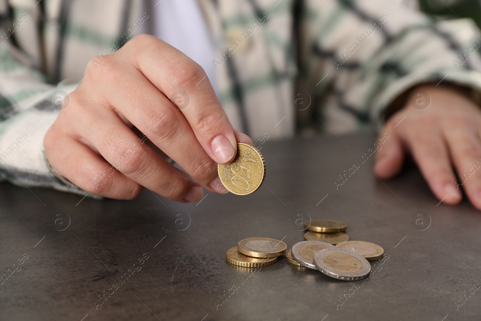 Photo of Poor woman counting coins at grey table, closeup