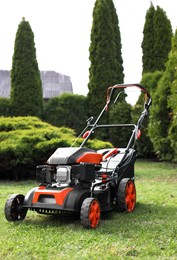 Modern lawn mower on green grass in garden