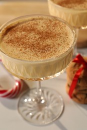 Photo of Tasty eggnog with cinnamon on white table, closeup