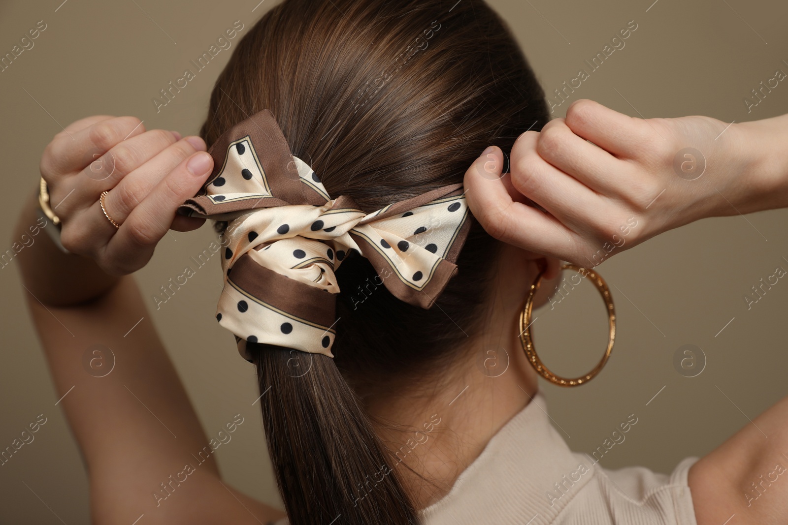 Photo of Young woman with stylish bandana on beige background, back view