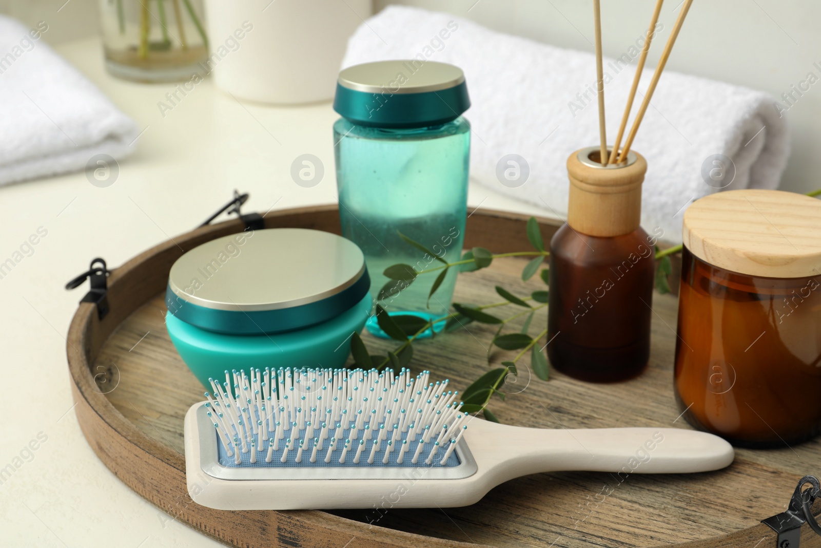 Photo of Hair care cosmetic products and brush on table indoors