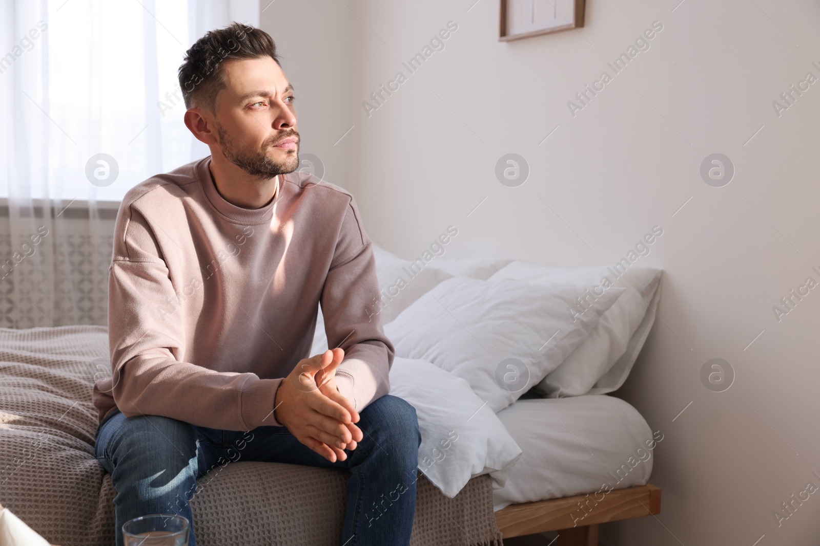 Photo of Upset man sulking at home, space for text. Loneliness concept