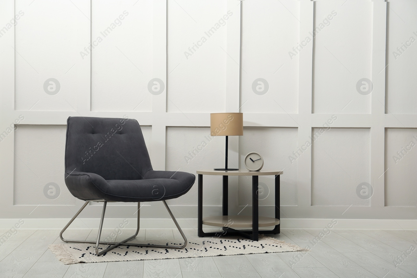 Photo of Modern grey armchair and small table near white wall indoors. Space for text