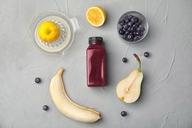 Photo of Flat lay composition with ingredients for delicious acai cocktail and bottle of juice on gray table