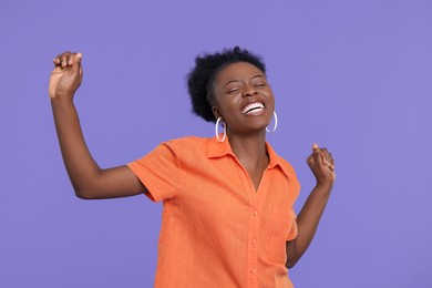 Photo of Happy young woman dancing on purple background