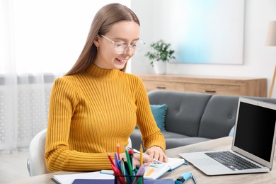 Woman taking notes at wooden table in office