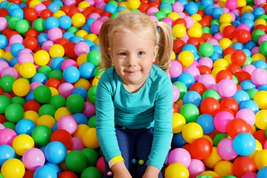 Photo of Cute child playing in ball pit indoors