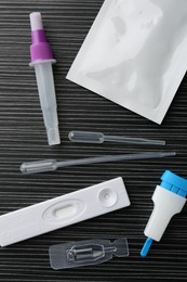 Disposable express test kit on black wooden table, flat lay