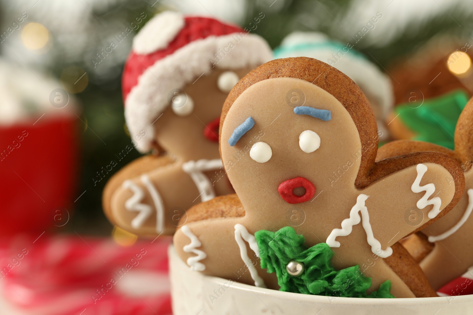 Photo of Delicious homemade Christmas cookies in bowl against blurred festive lights, closeup