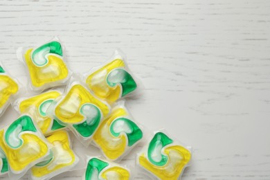 Photo of Many dishwasher detergent pods on white wooden table, flat lay. Space for text