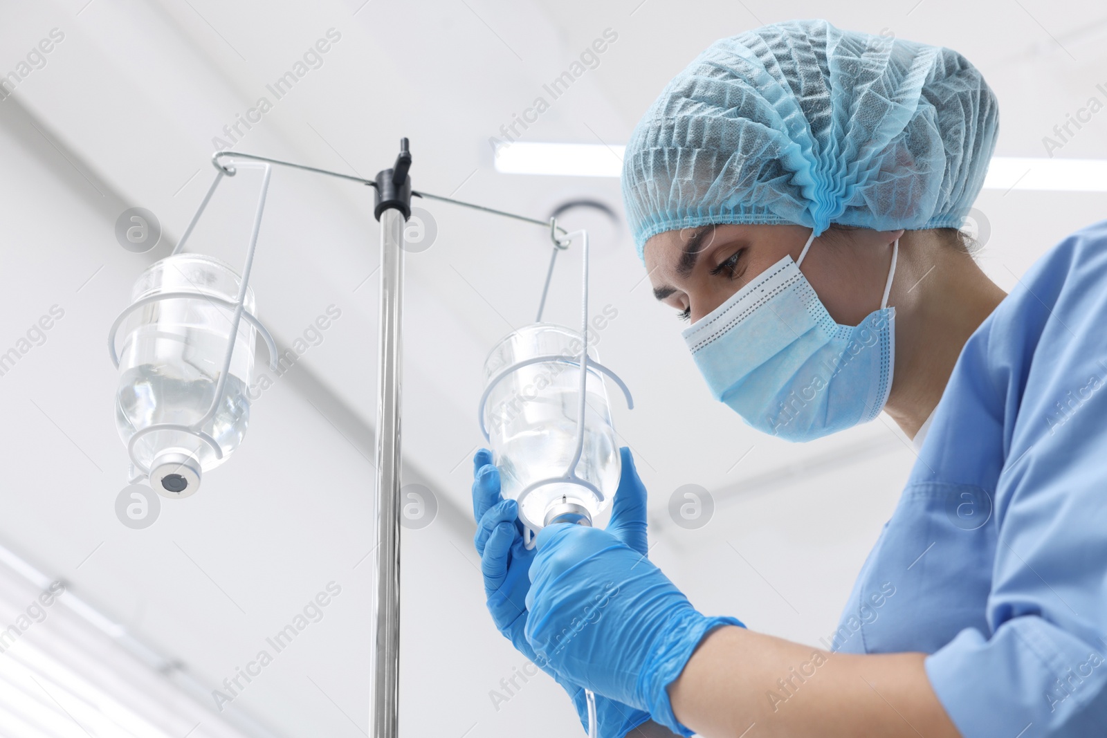 Photo of Nurse setting up IV drip in hospital, low angle view