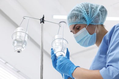 Photo of Nurse setting up IV drip in hospital, low angle view