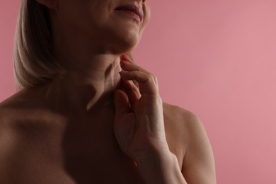 Photo of Woman touching her neck on pink background, closeup