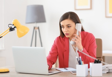 Young woman talking on phone at workplace