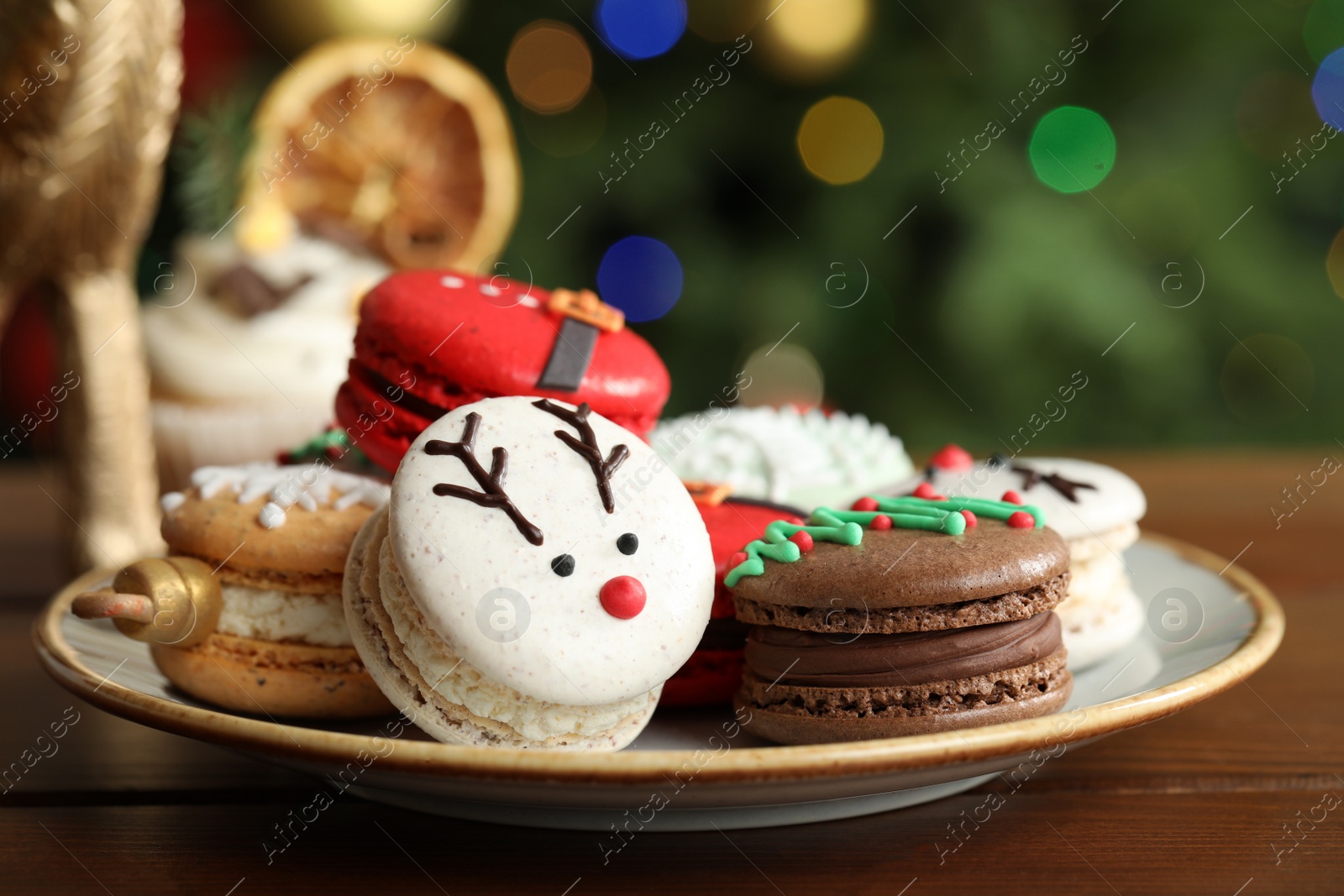 Photo of Beautifully decorated Christmas macarons on wooden table against blurred festive lights, closeup