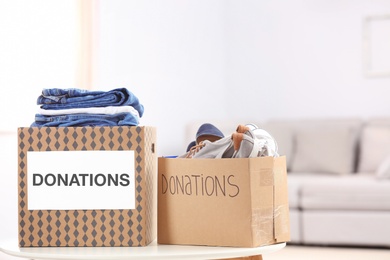 Photo of Donation boxes with clothes and shoes on table indoors