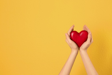 Photo of Woman holding decorative heart in hands on color background, space for text