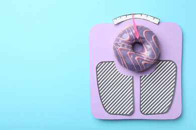 Photo of Scales made with donut on light blue background, top view. Space for text