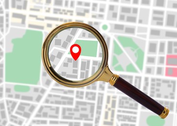 Image of Red location marker on city map, view through magnifying glass