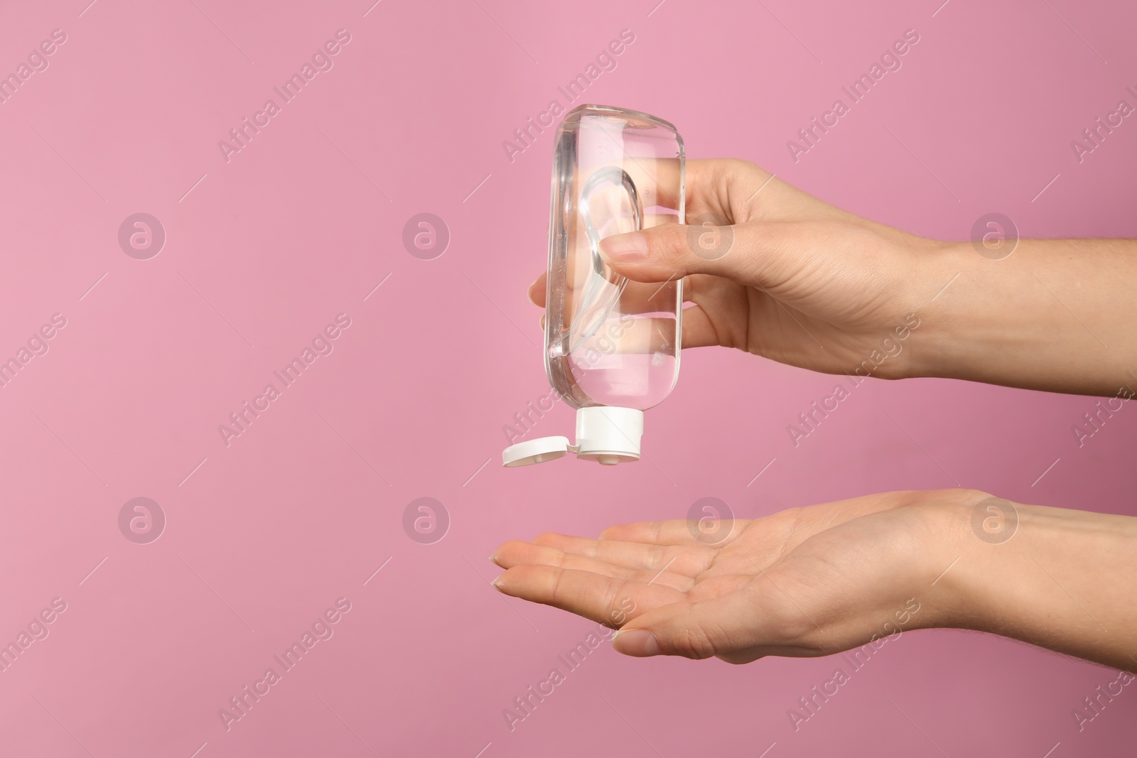 Photo of Woman applying antiseptic gel on pink background, closeup. Space for text