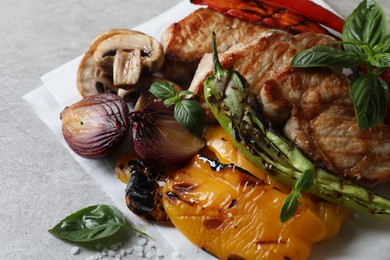 Tasty grilled meat and vegetables on light grey table, closeup